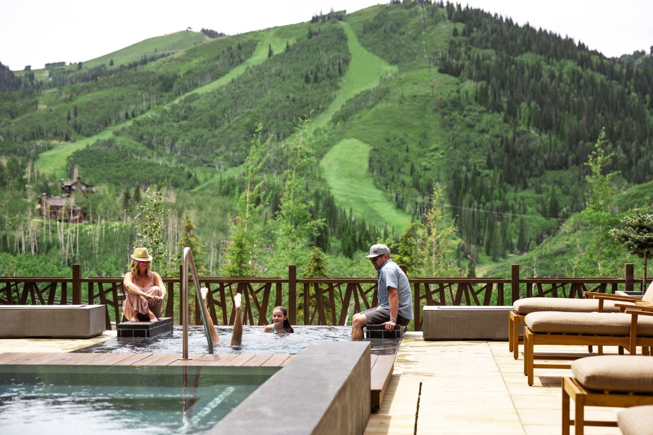 A family relaxing in a spa overlooking the mountains and ski runs.