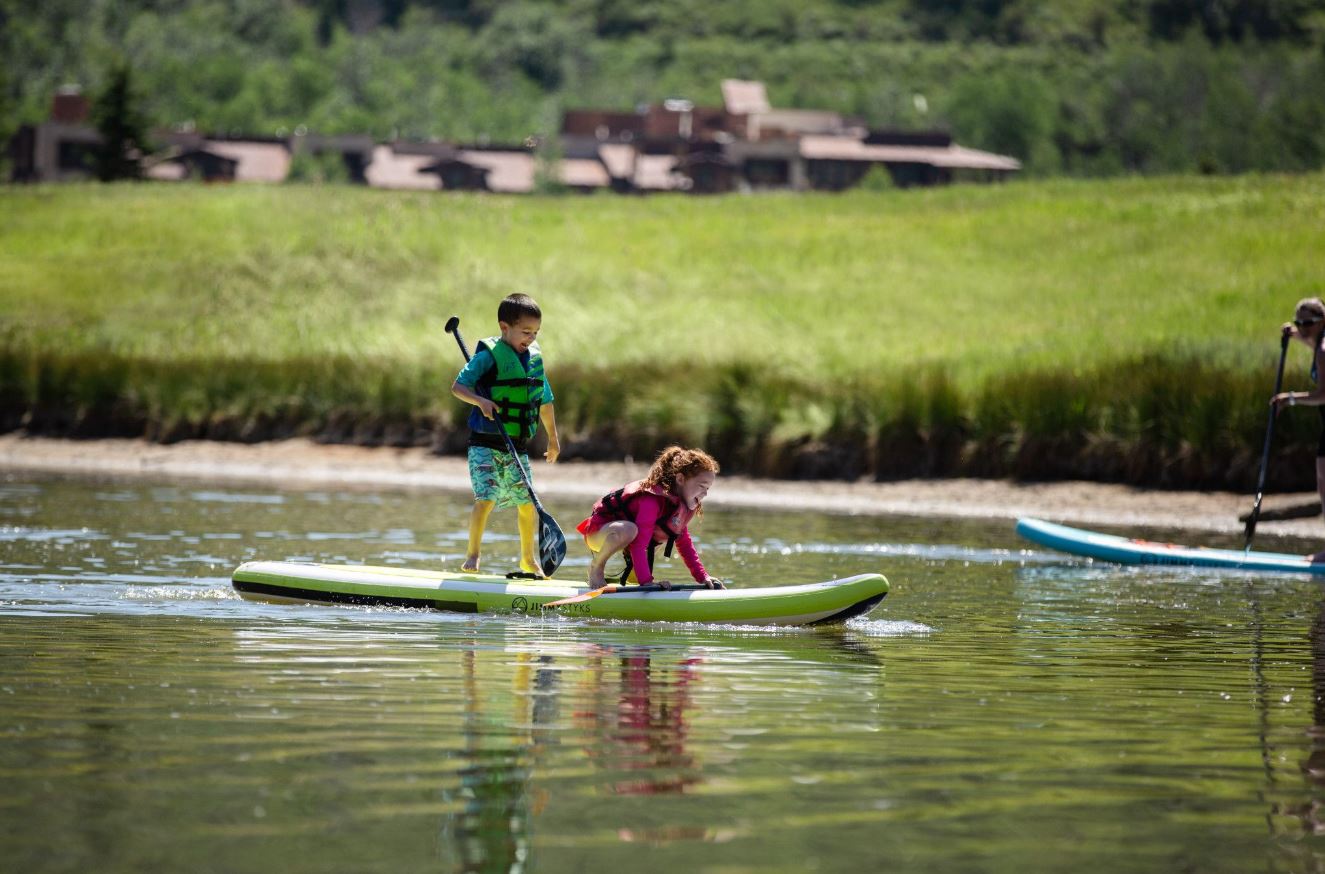 Two kids standup paddleboarding at Deer Valley Resort in Park City, Utah.